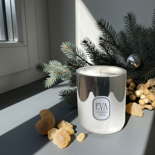 Candle in a silver holder with 'EVA CANDLES' branding, surrounded by decorative elements on a gray surface.