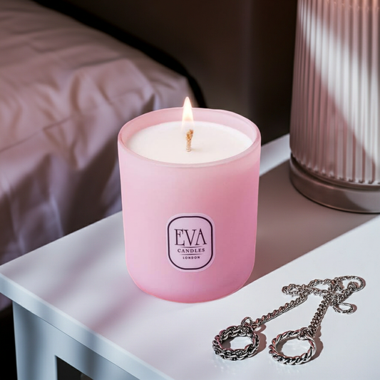 Luxury scented pink candle with 'EVA Candles London' branding on a table with a necklace.